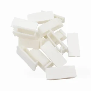Set of 20 black and white self-adhesive plastic cable clips arranged on a surface